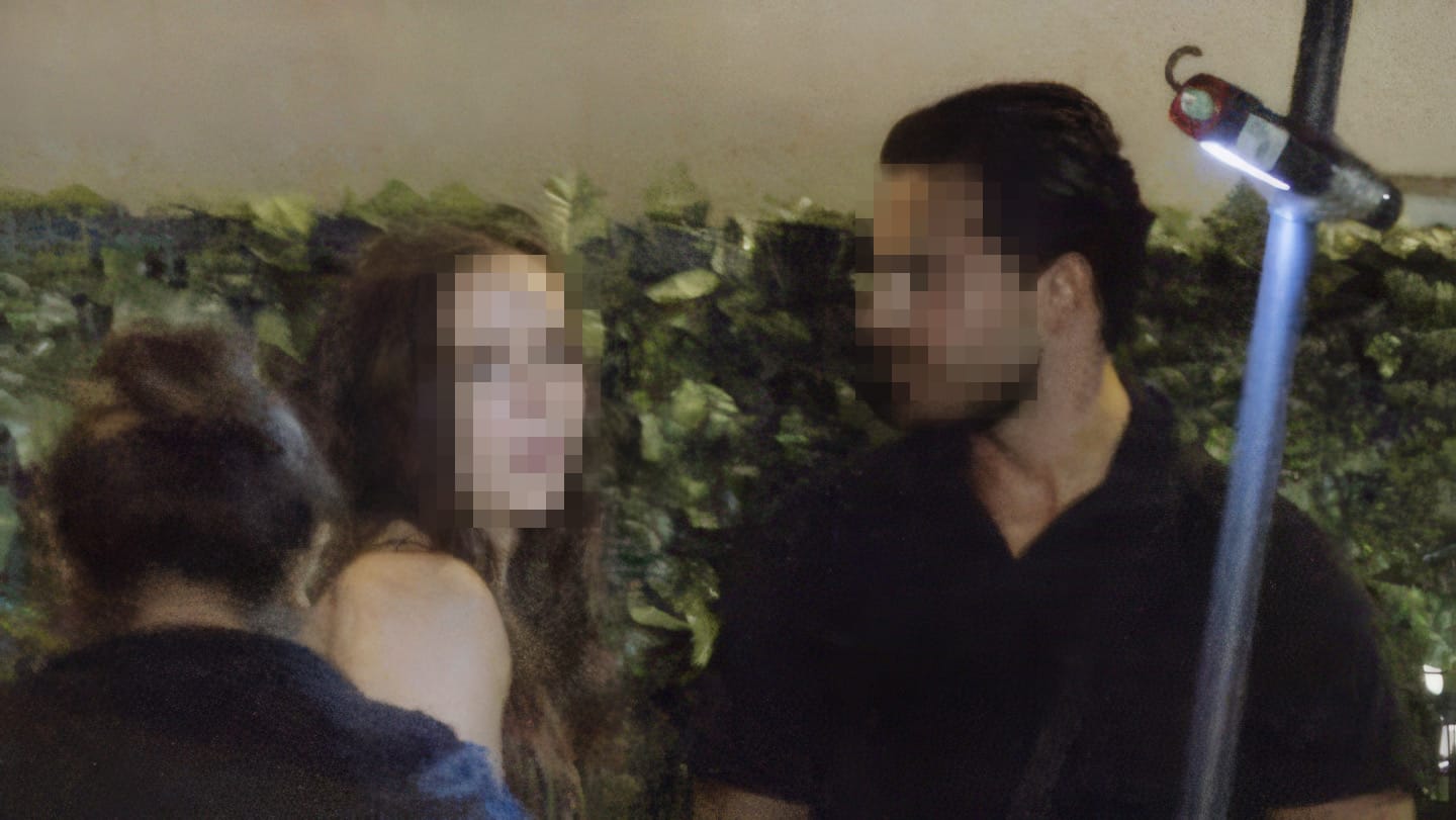 An individual suspected of infidelity engaged in a conversation with another person on a date at night, with both faces pixelated for privacy.